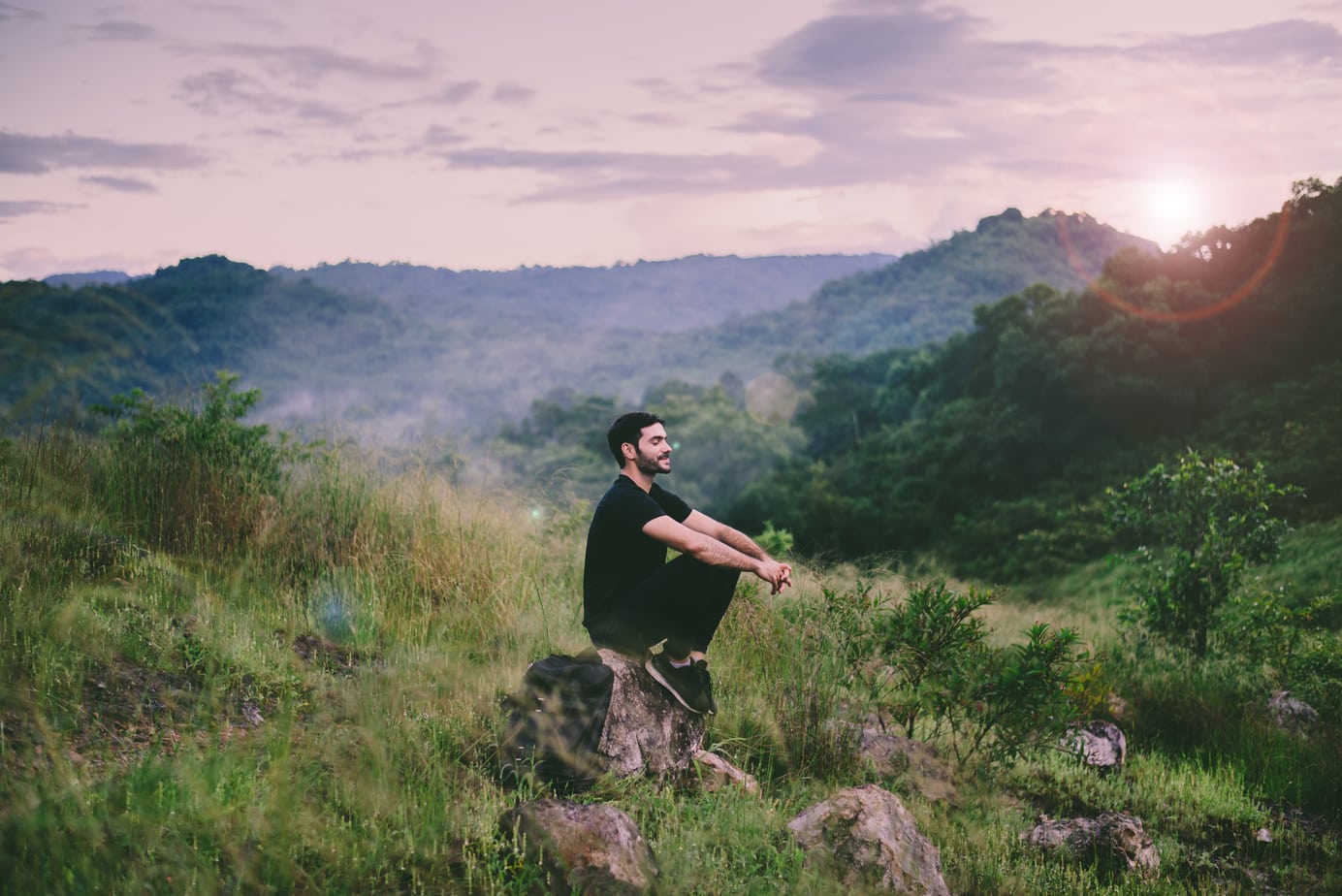 A man sitting meditating on a mountainside